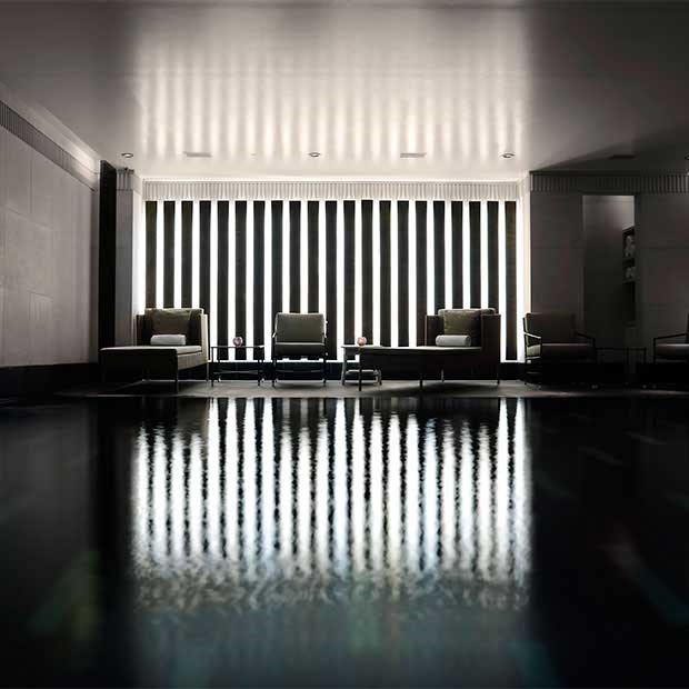 Intimate atmosphere and armchairs for relaxing next to the black granite swimming pool, in Aman Spa.