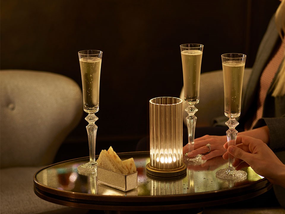 three glasses of champagne in ribbed flutes on table with bar snacks