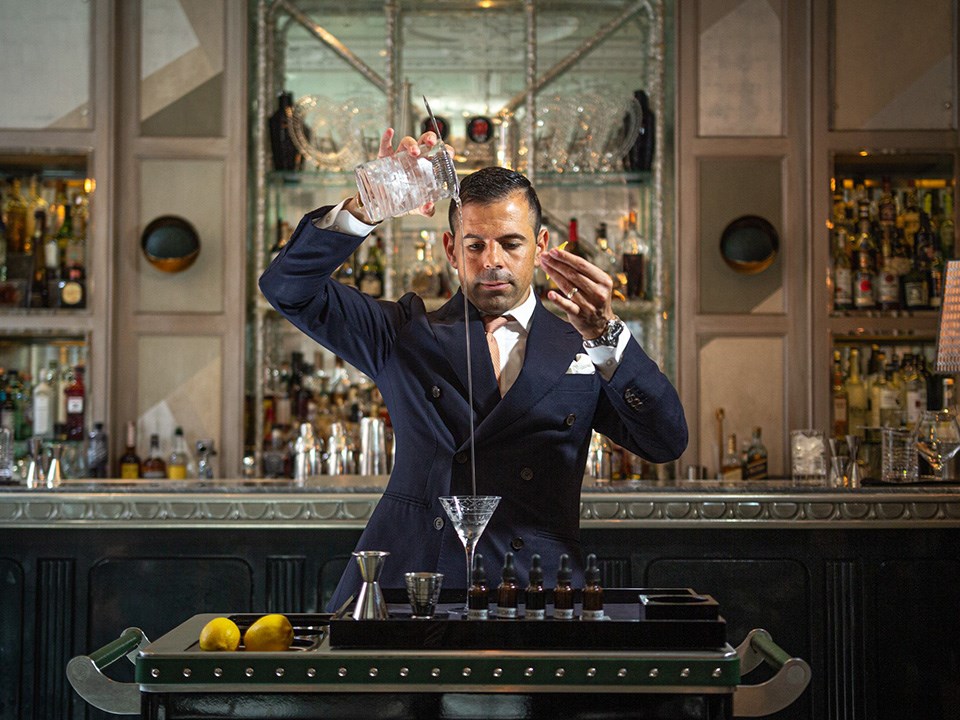 A focused mixologist in the process of making a delicious drink at The Connaught Bar.