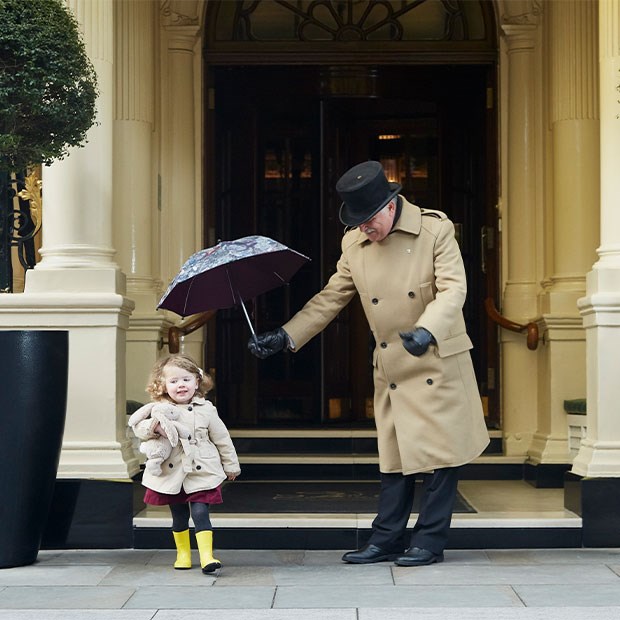 Doorman holds child's umbrella over the little girl