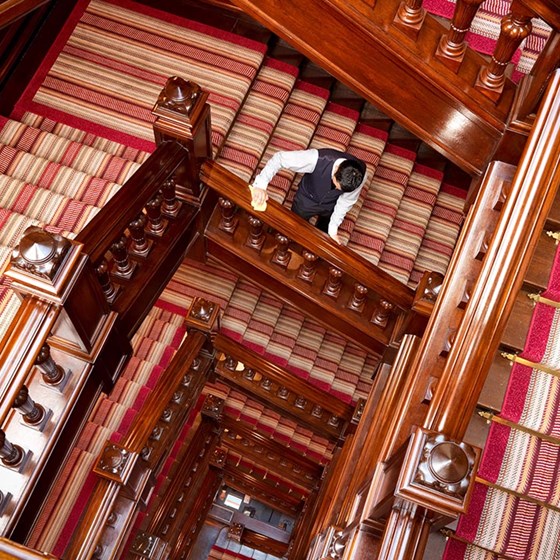 A depiction of a worker cleaning wooden bannisters from a staircase, at The Connaught hotel.