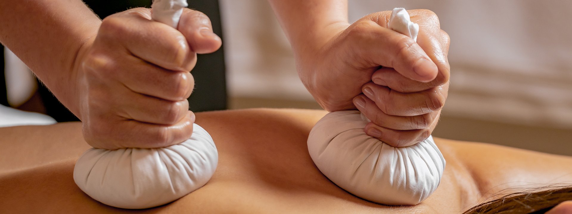 Two hands holding two small white bags.