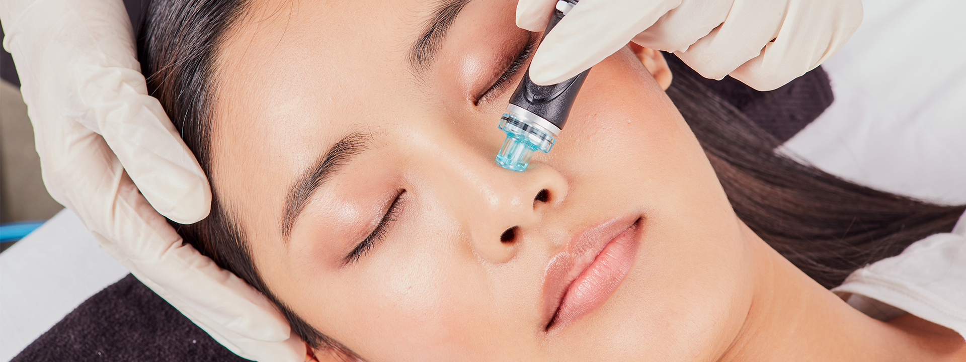 Woman having hydrofacial treatment with equipment resting on her forehead