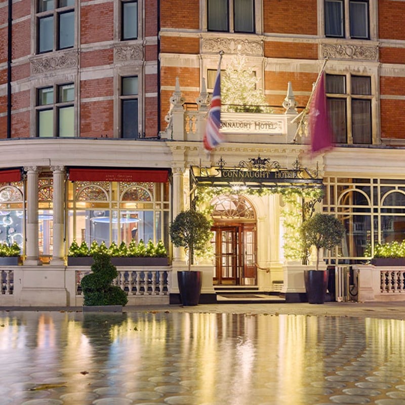 Exterior of The Connaught at night, with sparkling Christmas lights.