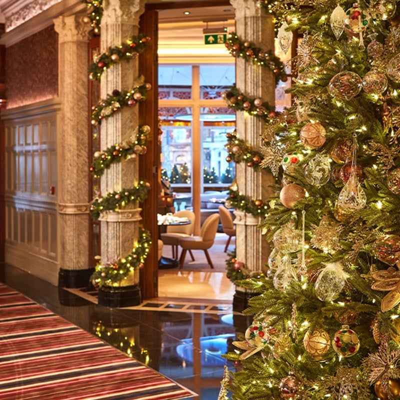 Entrance at The Connaught with a decorated Christmas tree in view, and pillars wrapped in festive decorated greenery.