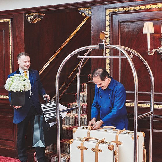 Smiling workers and concierges delivering flowers and luggage at The Connaught hotel.
