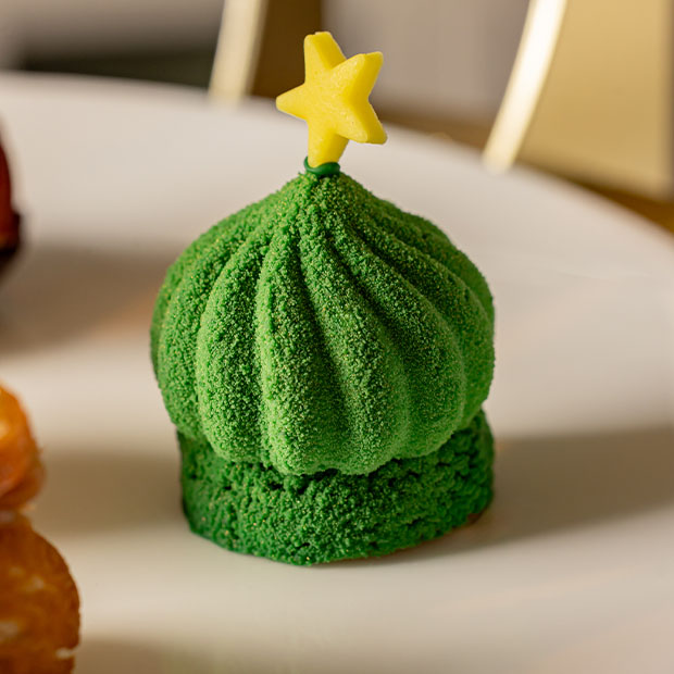 Green velvet-textured dome pastry with a small yellow star on top.