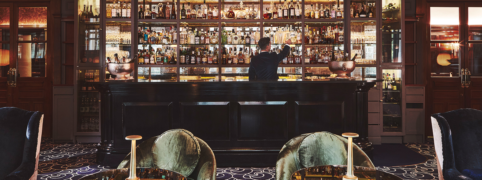 The Coburg spacious bar with lots of bottles and a team member behind the bar.