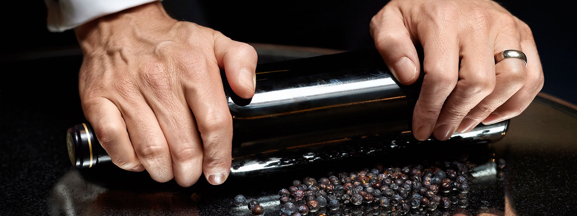 Showing hands crushing juniper berries, as an additional base for the drink.