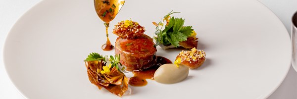 Helene Darroze Spring 2024 red meat dish with several garnishes including edible flowrs