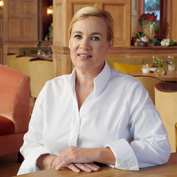 Helene Darroze in a white shirt, smiling in her restaurant