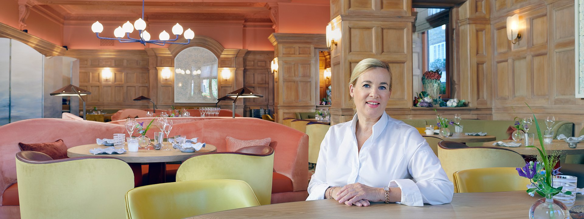 Helene Darroze dressed in a white shirt sitting in her restaurant.