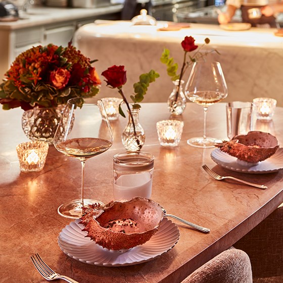 The setting of dishes on the table in a shell and glasses of wine in a romantic atmosphere.