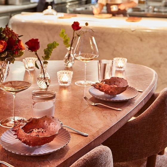The setting of dishes on the table in a shell, together with glasses of wine in a romantic atmosphere.