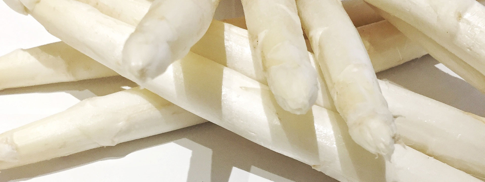 
Several white asparagus on a white surface.
