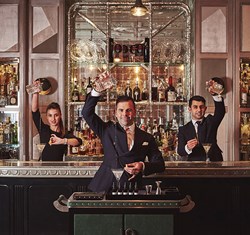 Three mixologists preparing drinks at The Connaught Bar, surrounded by the timeless elegance of the interior.