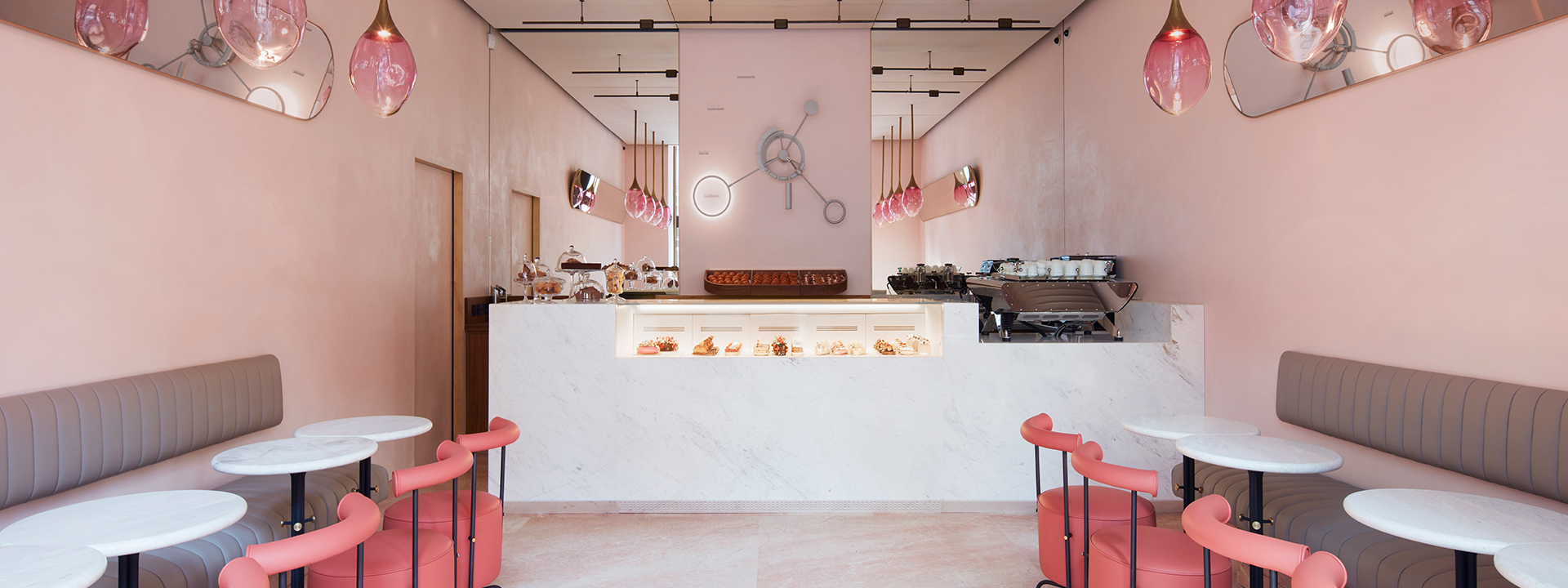 The pink interior of The Connaught patisserie; desserts on display modern seating area.