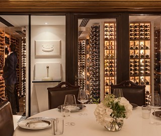 A presentation of a lavish amount of wine at The Sommelier�s Table, with a sommelier selecting wine from the rack.