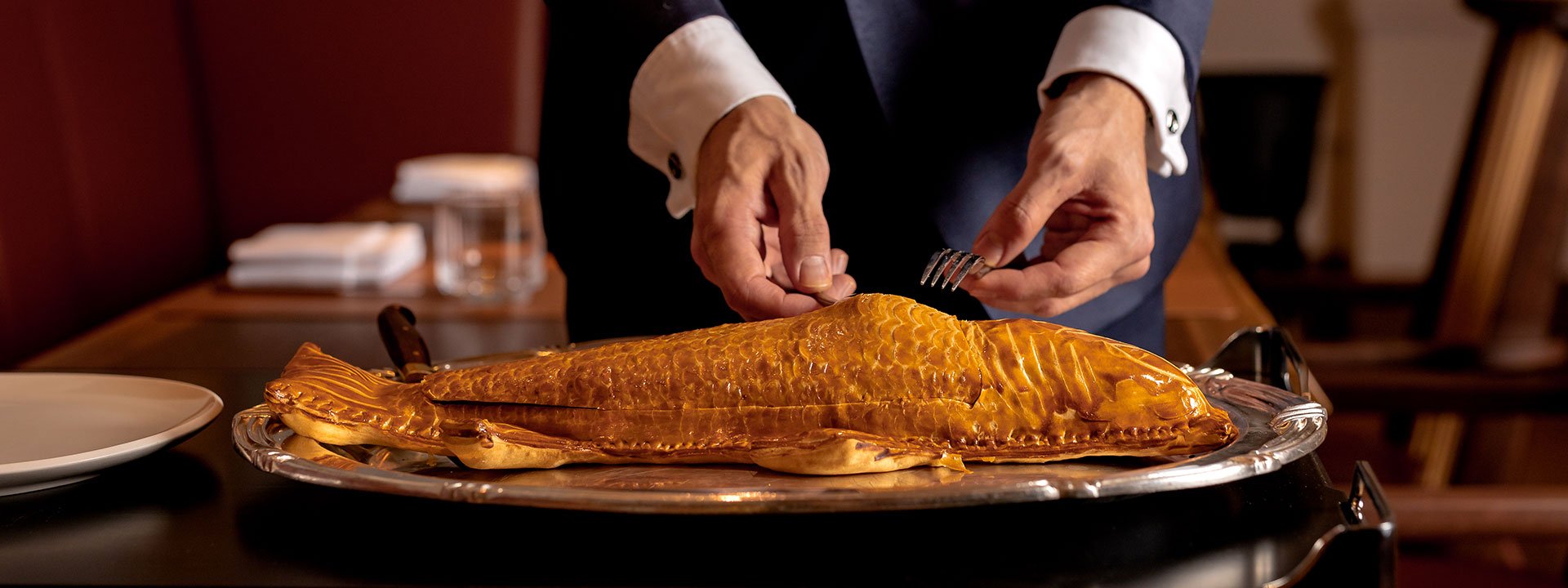 Presentation of whole wild sea bass en croute is shaped and decorated to look like the fish at The Connaught Grill.