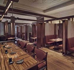 A view of part of The Connaught Grill, with lots of booths and dining tables, in the warm atomosphere.