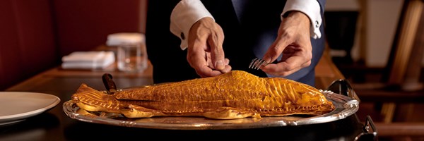 Presentation of whole wild sea bass en croute is shaped and decorated to look like the fish at The Connaught Grill.