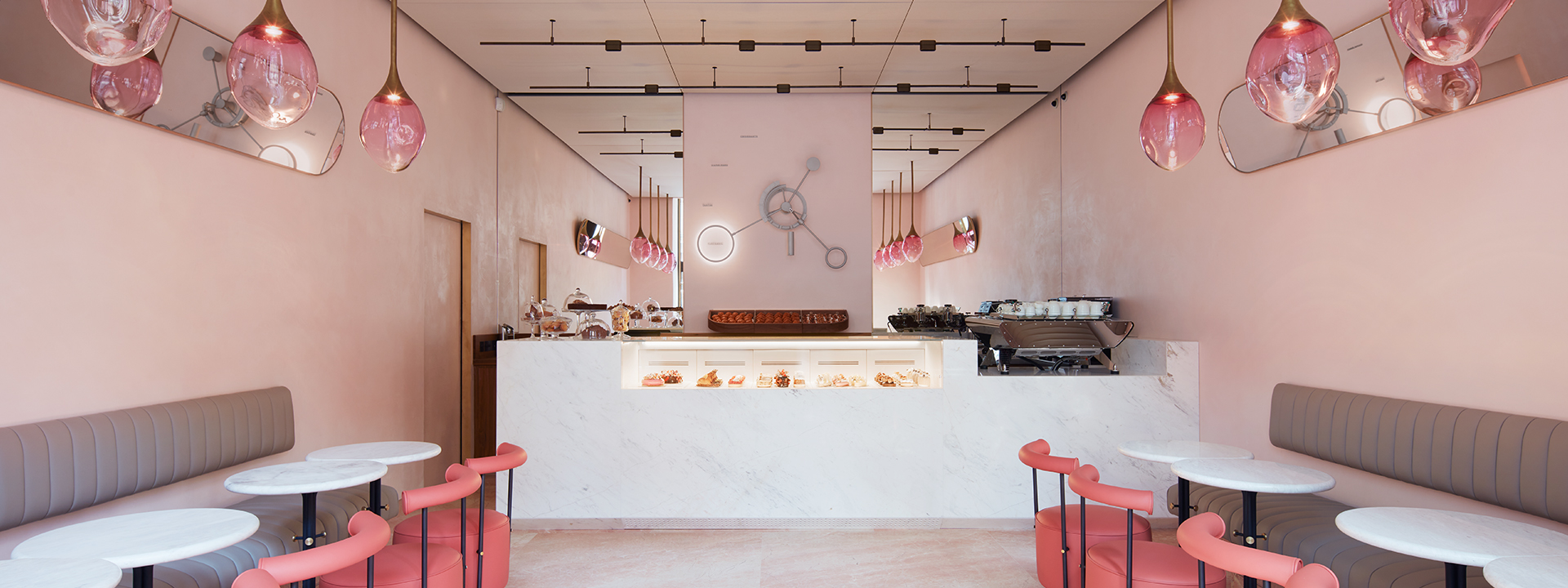 The pink interior of The Connaught patisserie; desserts on display modern seating area.