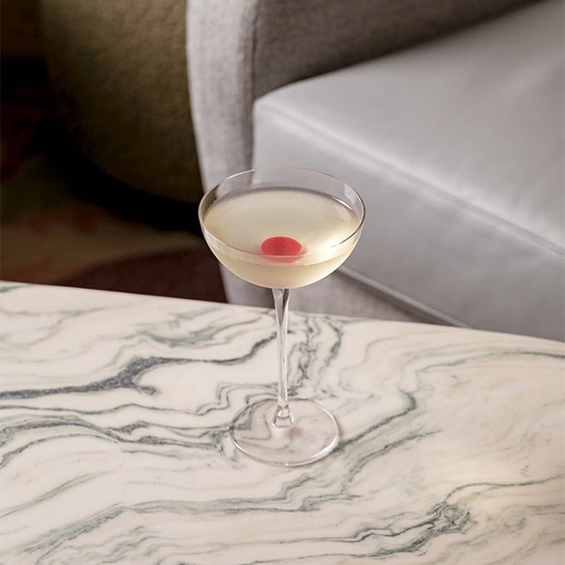 Martini with a red base on a marble table.