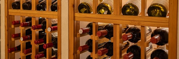Close-up of a wooden wine rack filled with bottles of red and white wine, showcasing the labels and corks nestled within individual wooden compartments.
