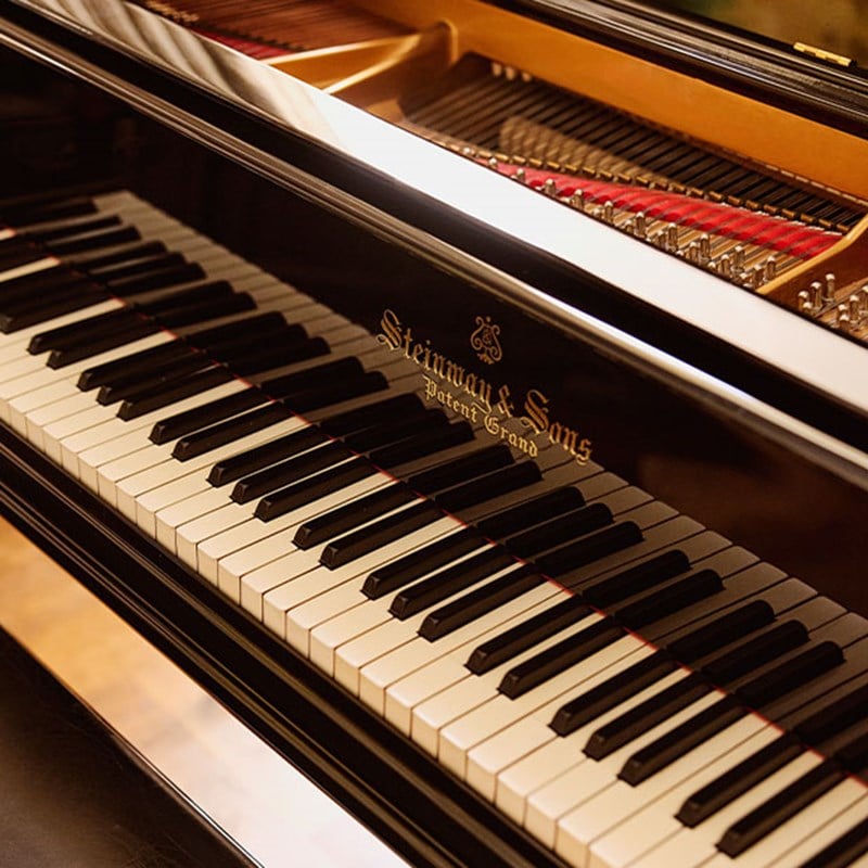 Close-up of a black Steinway & Sons grand piano showing the polished keys and part of the open strings inside.