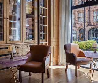 The Connaught Cigar Merchants inside view with armchair, marble table, cupboard with glassdoors and view on a street of London.