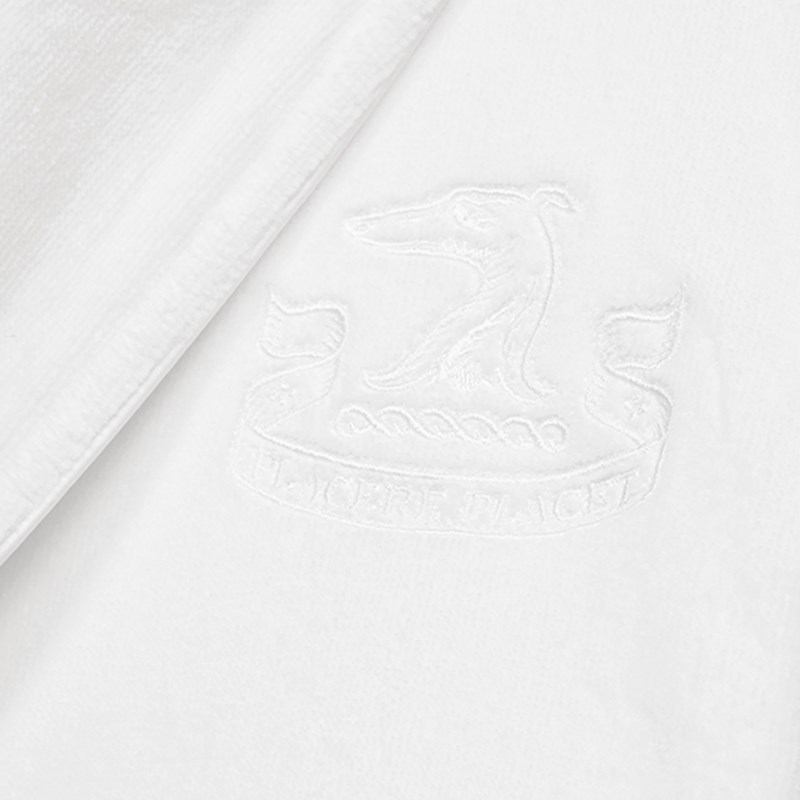 Photo of details on the white bathrobe, where it has an embroidered dog logo.