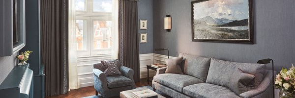 Coburg Suite: living area with sofa, coffee table, books, painting at the back of the room