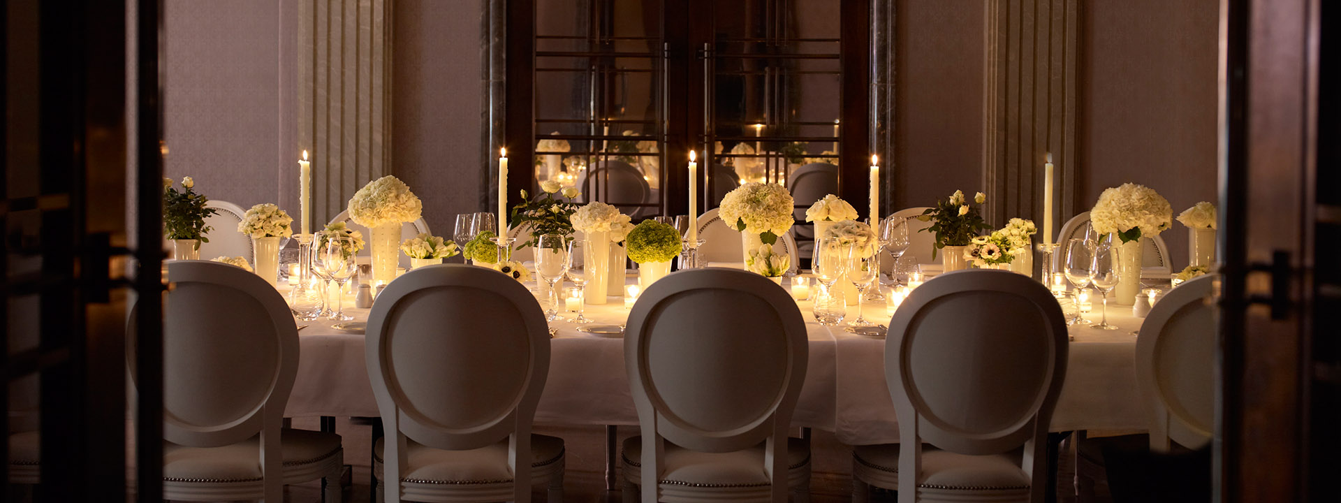 A romantically set table in the Mayfair Room, at The Connaught, decorated with floral arrangements and candles.