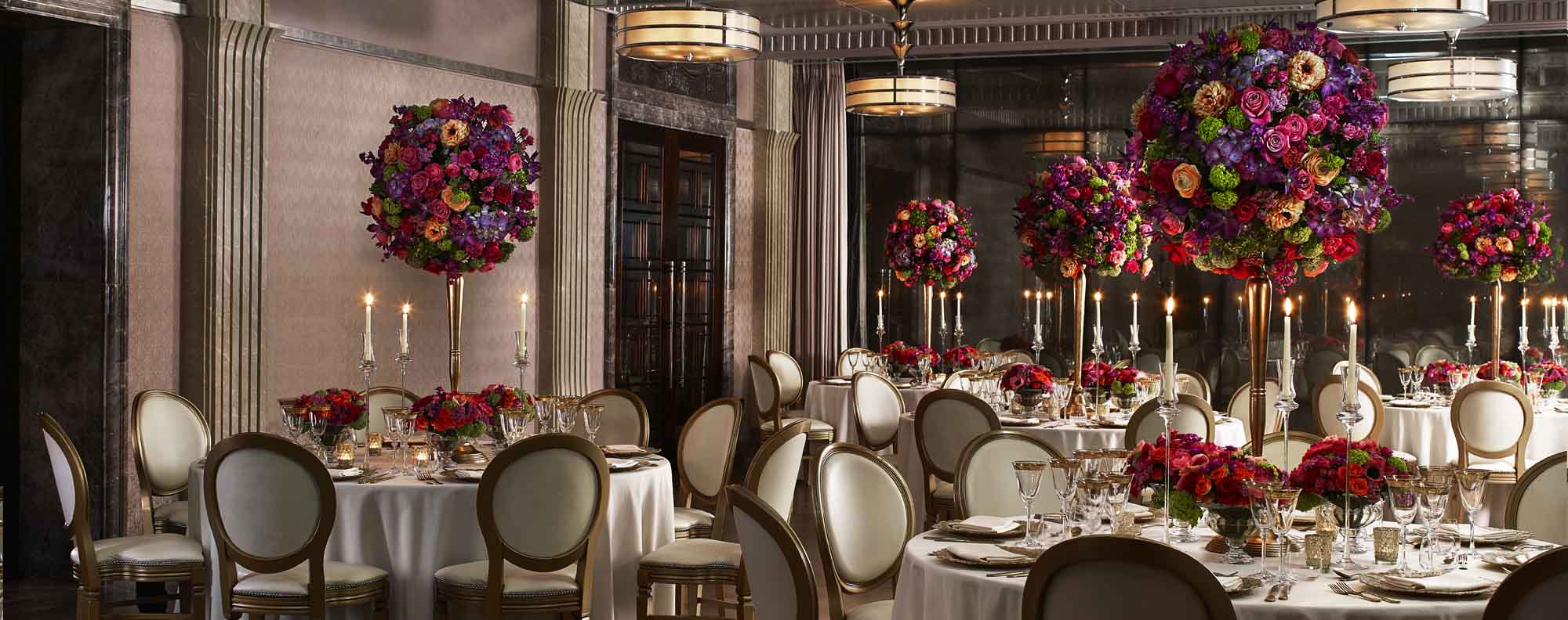 Large round tables with white seats and colourful decorative flowers in the Mayfair Room.