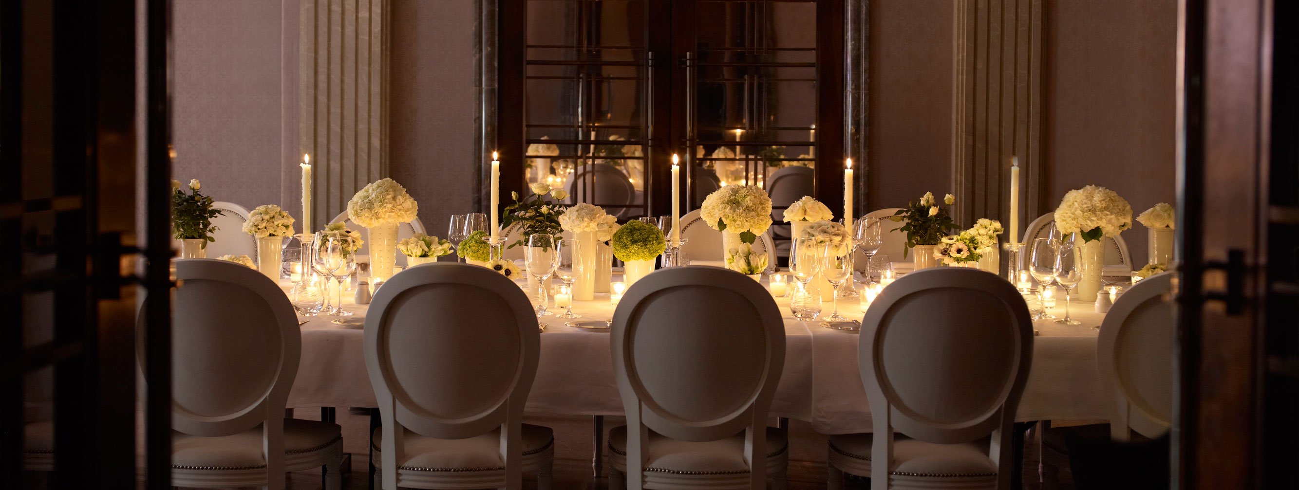 A romantically set table in the Mayfair Room, at The Connaught, decorated with floral arrangements and candles.