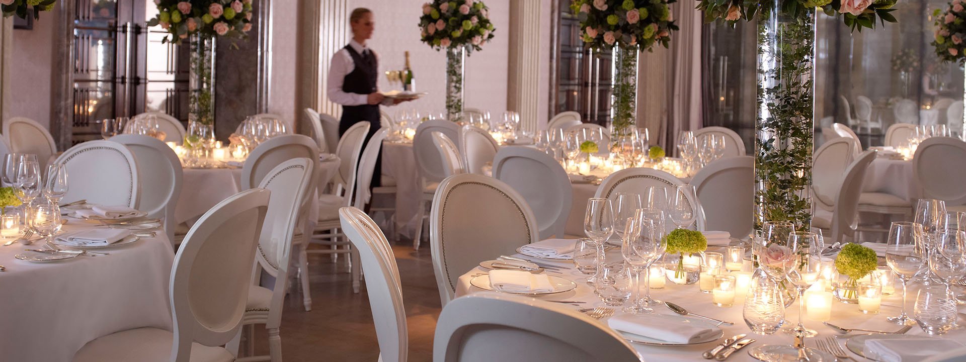 Presentation of decorated tables with flower arrangements and candles at The Connaught, for a wedding.