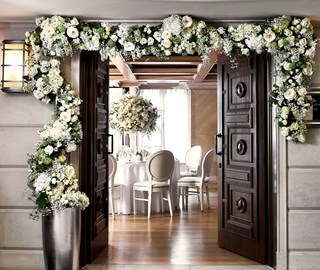 The Maple Room at The Connaught with beautiful flowers above the entrance door and a round table set up for a wedding reception