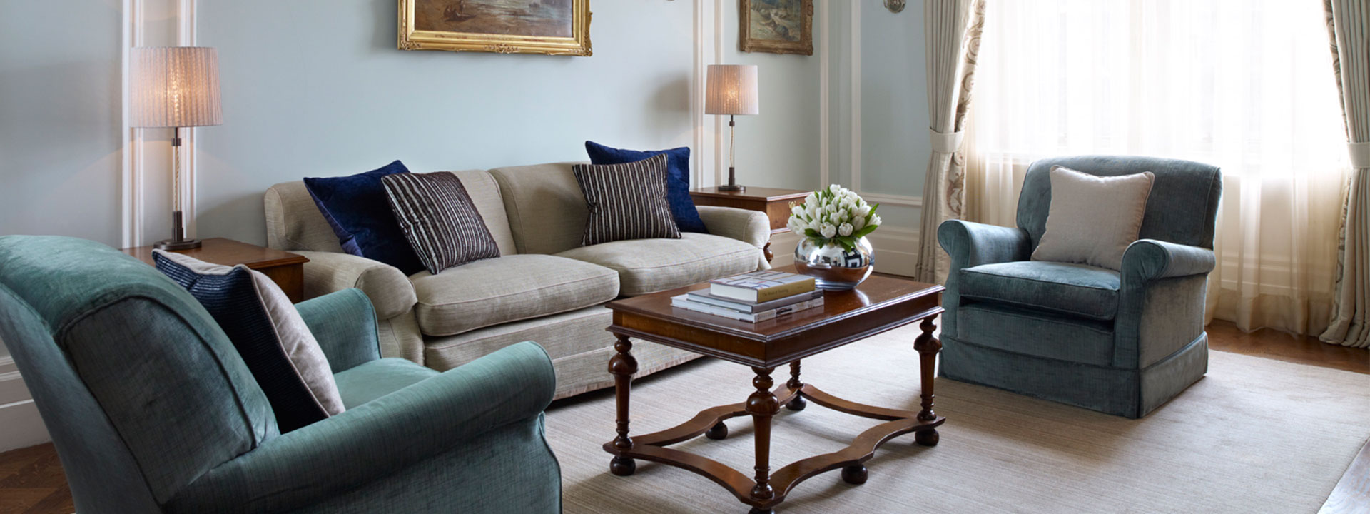 Comfortable armchairs and a sofa, in cream and blue colours from Carlos Suite, in an elegant interior.