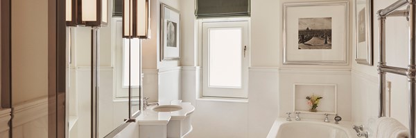 Coburg Suite bathroom: Mirrors and two sinks on the left, a window at the back, and a bath on the right.