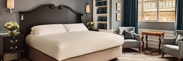 Sophisticated bedroom with a dramatic black headboard, deep blue curtains, and built-in bookshelves