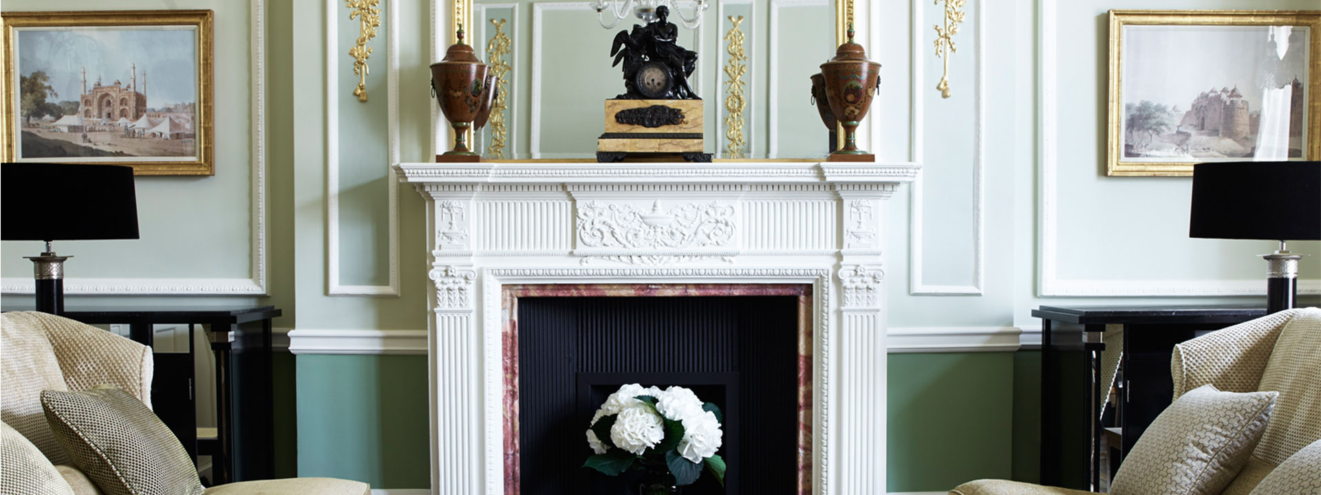 The original ornate fireplace in The Connaught suite, artwork on the wall, and luxurious interior details.