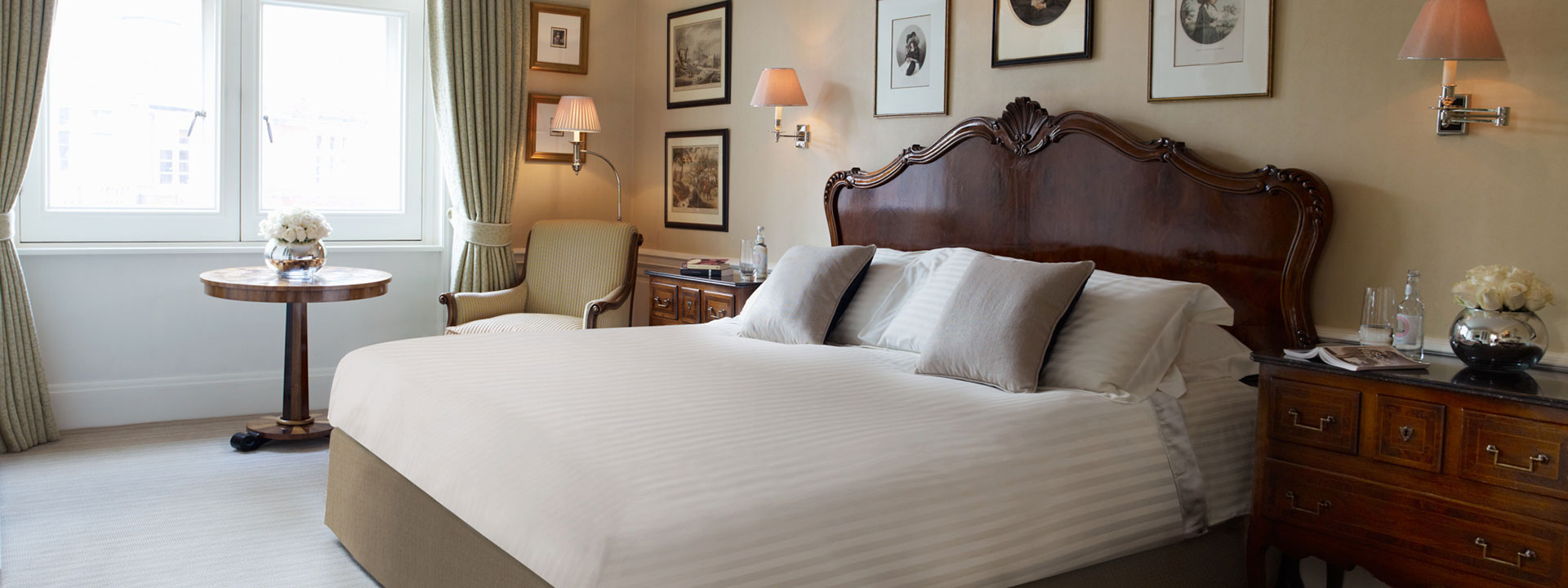Comfortable and spacious queen bed with an little wood table by a bright window at The Connaught suite.