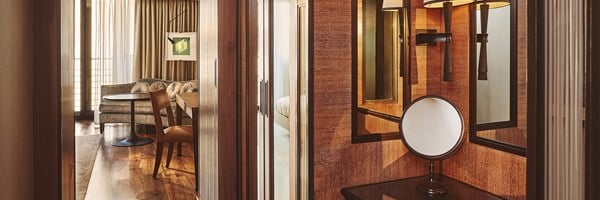 Warm hallway leading to a velvet sofa and table, with mirrors and wood panel accents.