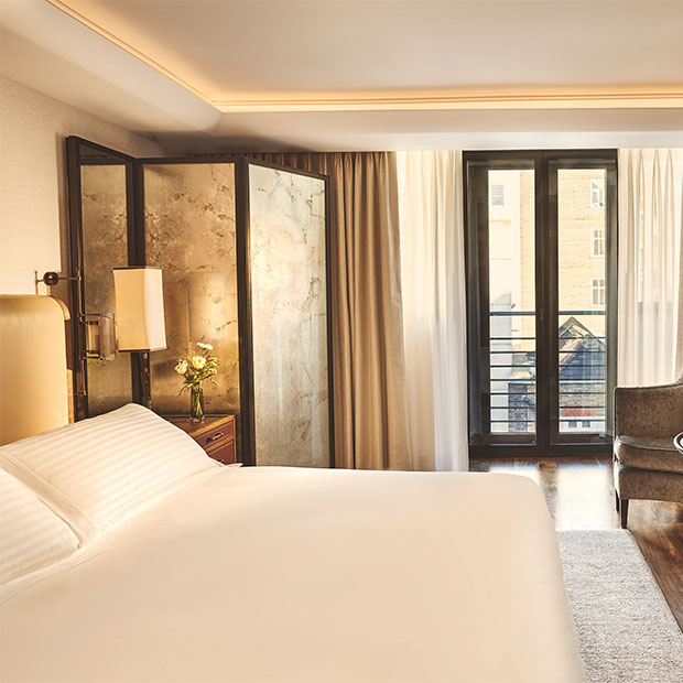 “Bedroom with a light upholstered headboard, marble screen and floor-to-ceiling windows