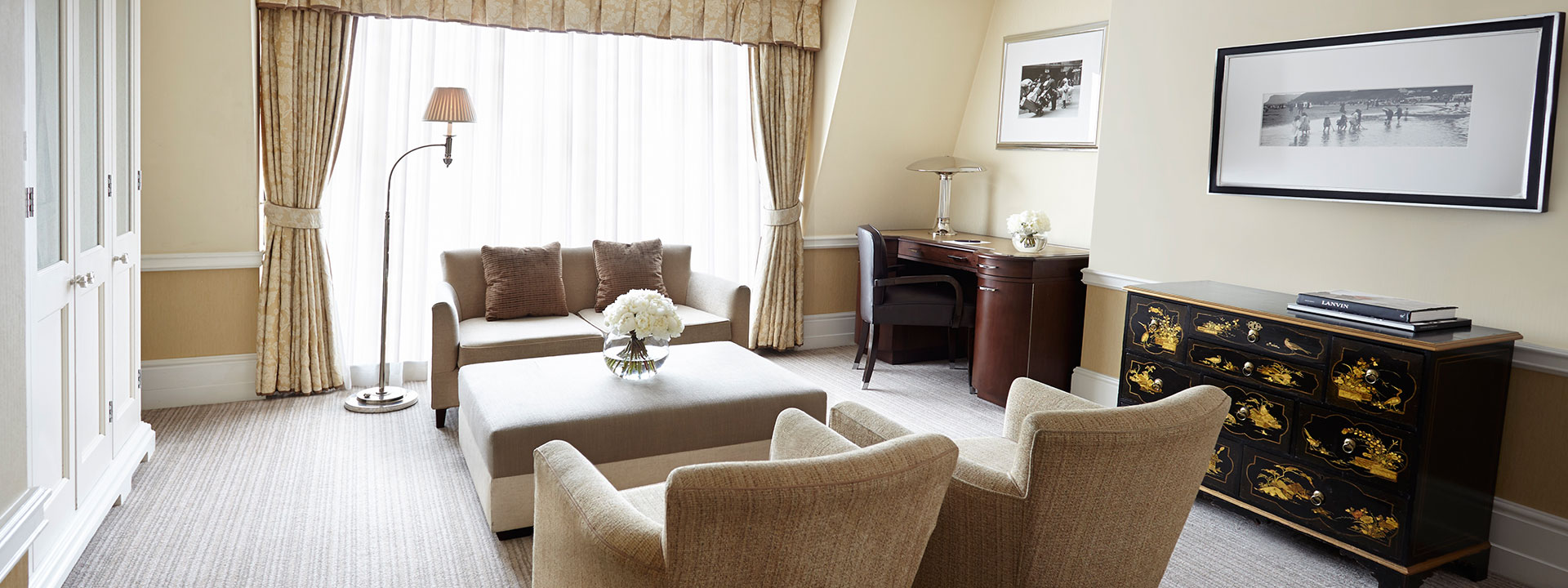 Sitting area in classic interior style, beige sofa and armchair in the Deluxe Junior Suite at The Connaught.