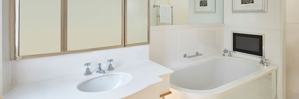 white bath with tv on the wall, and sink