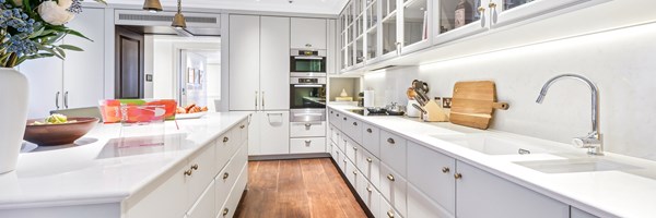 Bright kitchen view with marble countertops, integrated appliances, ample cabinetry, and fresh flowers arranged on the central island.