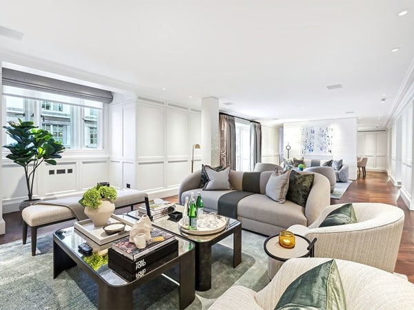Spacious, design-led living room in a Connaught residence, featuring curved sofas, mid-century modern furnishings, and large windows that fill the space with natural light.