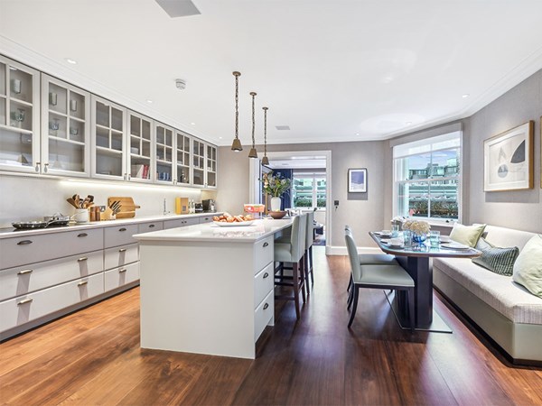 Bright, open-plan kitchen in a Connaught residence, with an island breakfast bar, contemporary cabinetry, and a built-in dining nook overlooking Mayfair rooftops.
