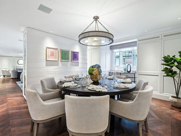 Refined dining area with a round table set for eight, soft upholstered chairs, a modern chandelier, and panelled walls reflecting the classic Connaught style.